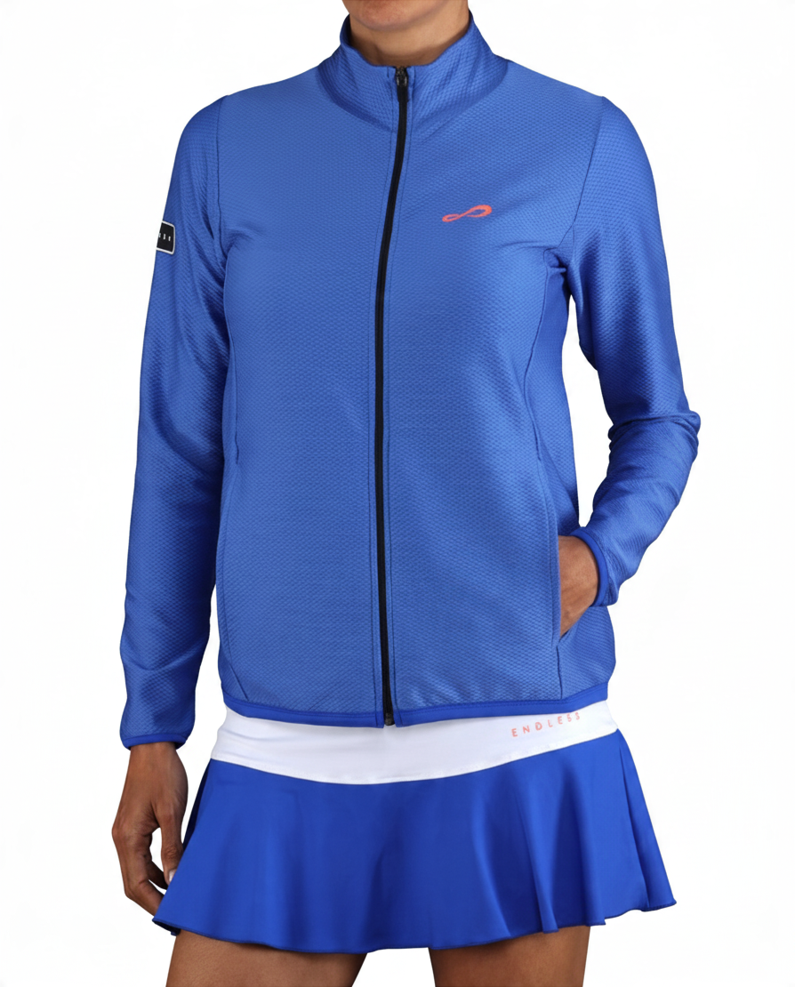Chaqueta deportiva Endless MX azul de mujer con cuello alto, cremallera y bolsillos, ideal para tenis y pádel.