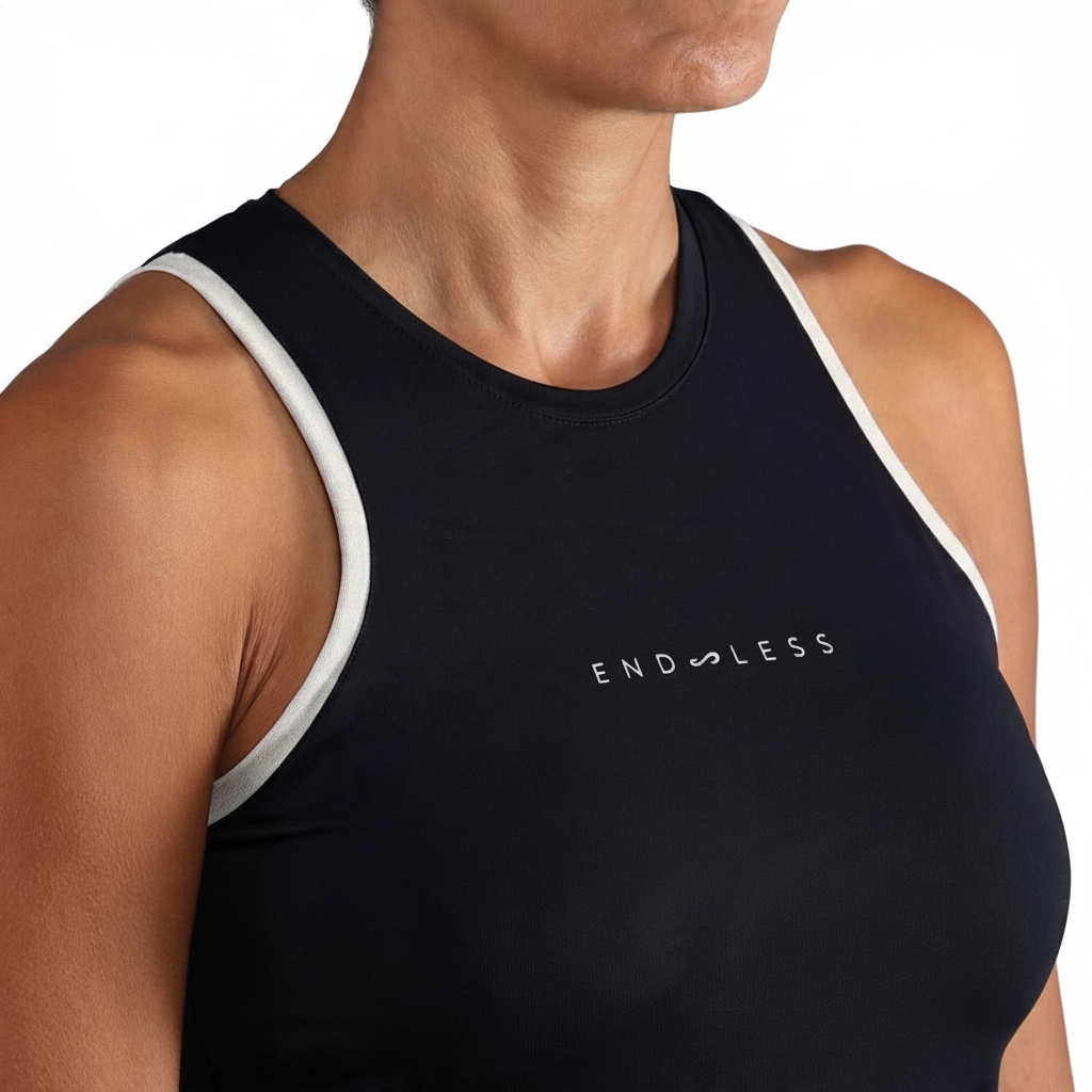 Top deportivo Endless MX negro con cuello cerrado y detalles en contraste blanco para tenis y pádel.
